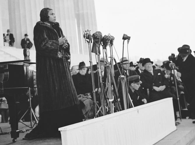 Marian Anderson stands outside before a bank of microphones, preparing to sing from the steps of the Lincoln Memorial before an audience of thousands of people gathered on the National Mall