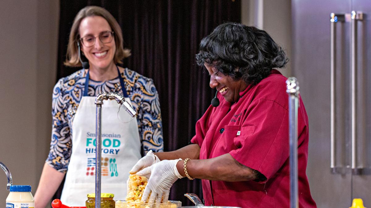 Two women deliver a cooking demonstration on stage